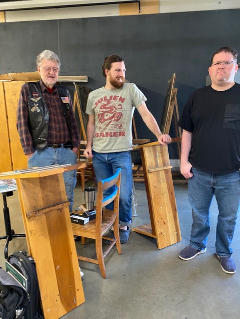 Three artists talking next to their drawing boards.